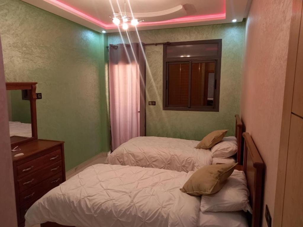 - une chambre avec 2 lits, un miroir et des lumières roses dans l'établissement Agadir vibes appartement, à Agadir
