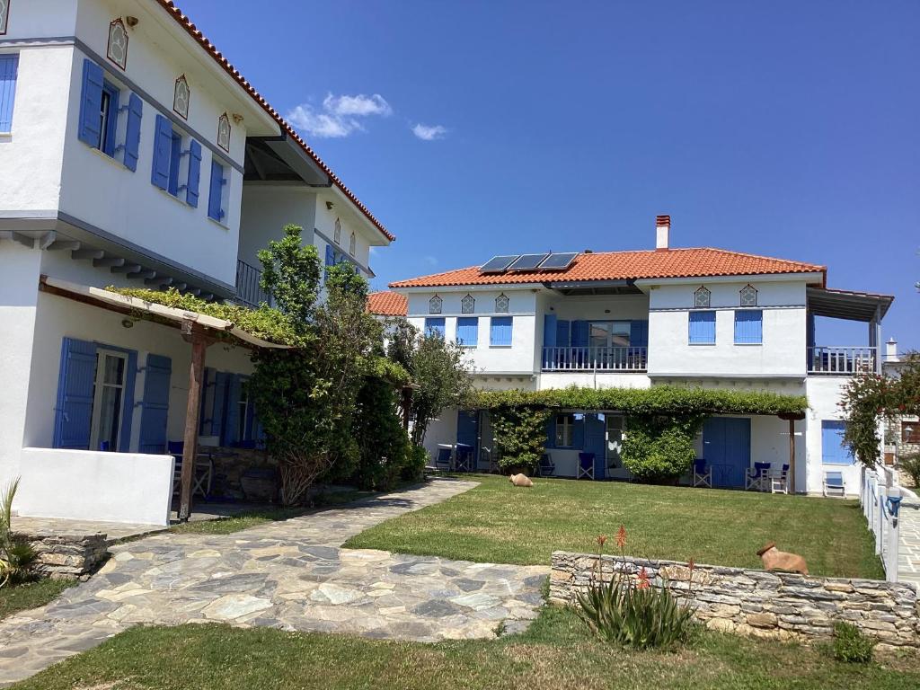 una casa bianca con finestre blu e un cortile di Aktaion Hotel a Kálamos