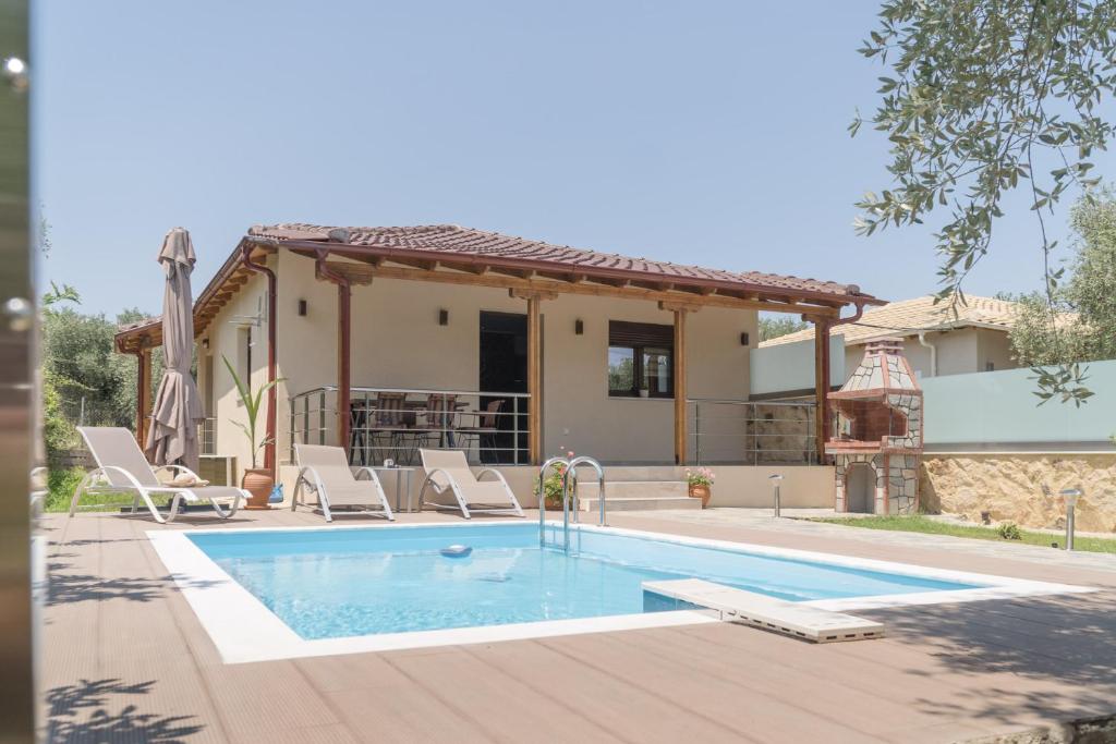 einen Pool mit Stühlen und ein Haus in der Unterkunft LUXURY VILLAS ELENI STEFI in Limenas