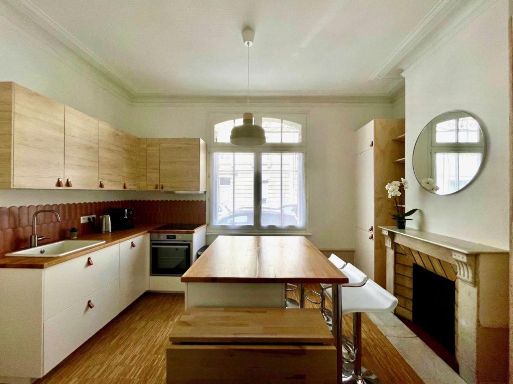 une cuisine avec des armoires blanches et une table en bois dans l'établissement Maison familiale proche centre ville, à Amiens