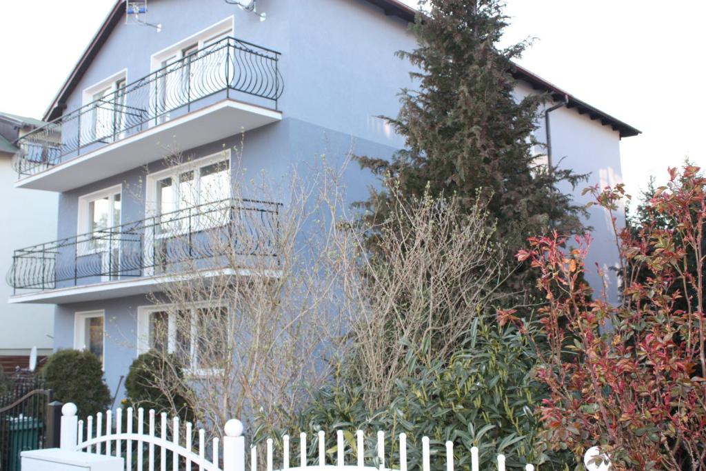 a blue house with a white fence in front of it at Ugeni ,apartament in Ostrowo