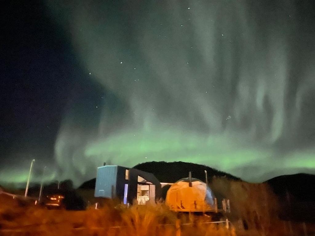 an image of the aurora in the sky over a building at Storjord Farmstay Glamping in Tromsø