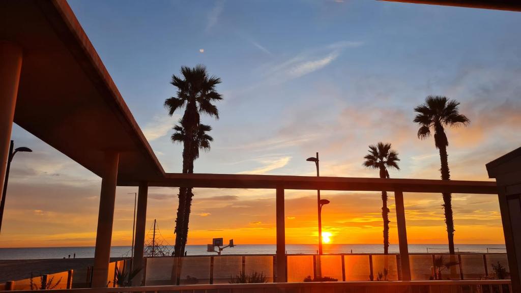 puesta de sol sobre la playa con palmeras en BEACH VALENCIA 29 - Luxury Beachfront Apartament, en Valencia