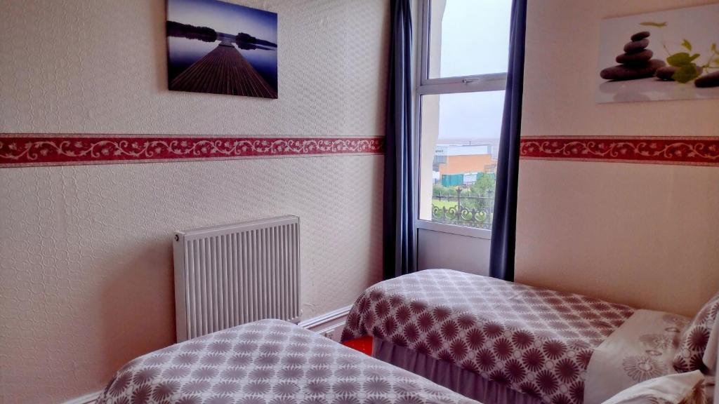 a small room with two beds and a window at The Kathrene in Fleetwood
