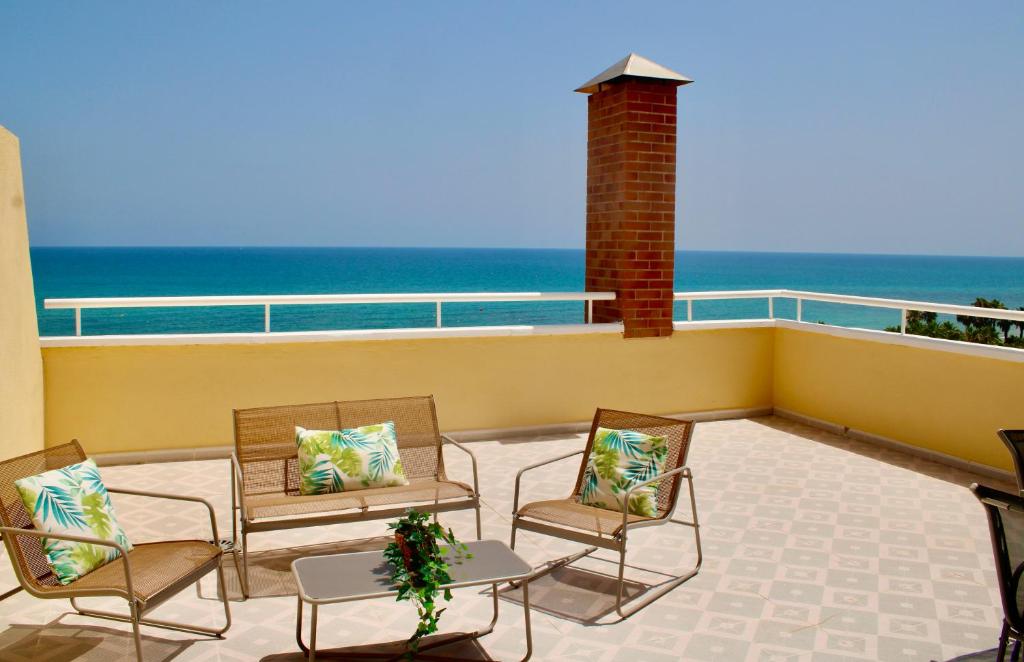 uma varanda com cadeiras e uma mesa e o oceano em Primera línea de mar con terraza ático en Magic World - Marina Dor em Oropesa del Mar