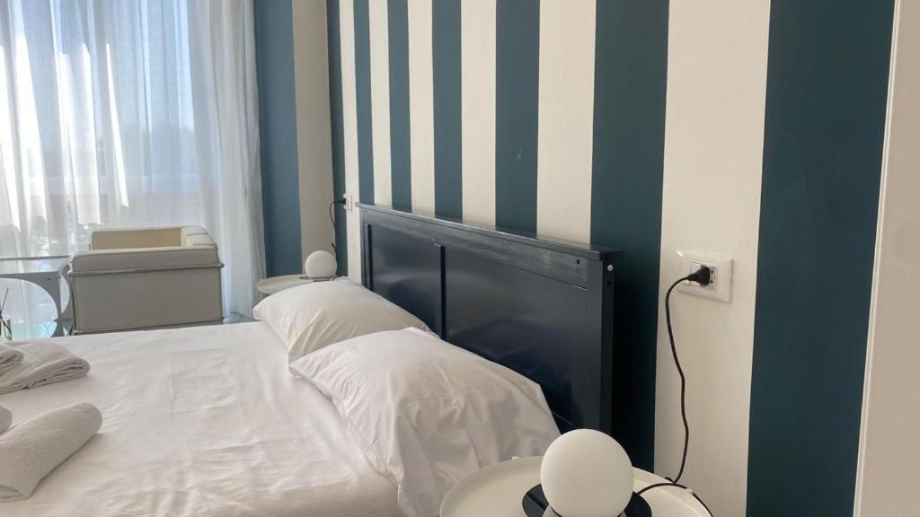 łóżko z paskowym zagłówkiem w sypialni w obiekcie Stupenda camera vista mare con finiture di lusso w mieście Marina di Carrara