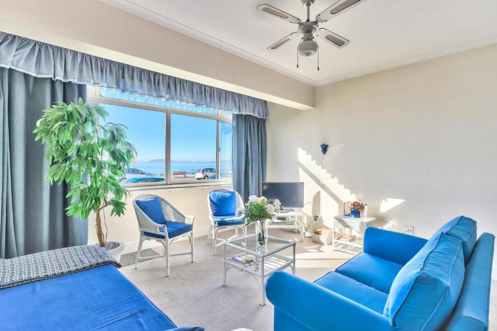a living room with blue furniture and a large window at 3 Sandringham Sea Facing ground-floor Studio in Cape Town