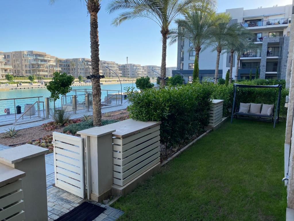 a garden with palm trees and a view of the water at Marassi Marina Residences in El Alamein
