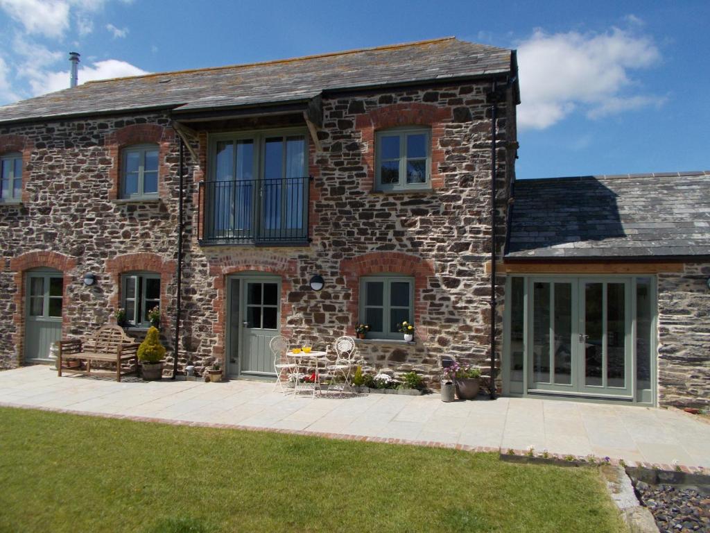 a stone house with a patio in front of it at The Barn At Collacott in North Petherwin