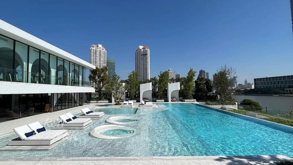 a large swimming pool with lounge chairs and a building at Luxury River View in Bangkok