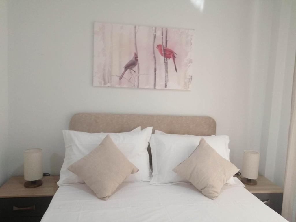uma cama com almofadas brancas e uma fotografia na parede em Argostoli Elia's Maisonette em Argostólion