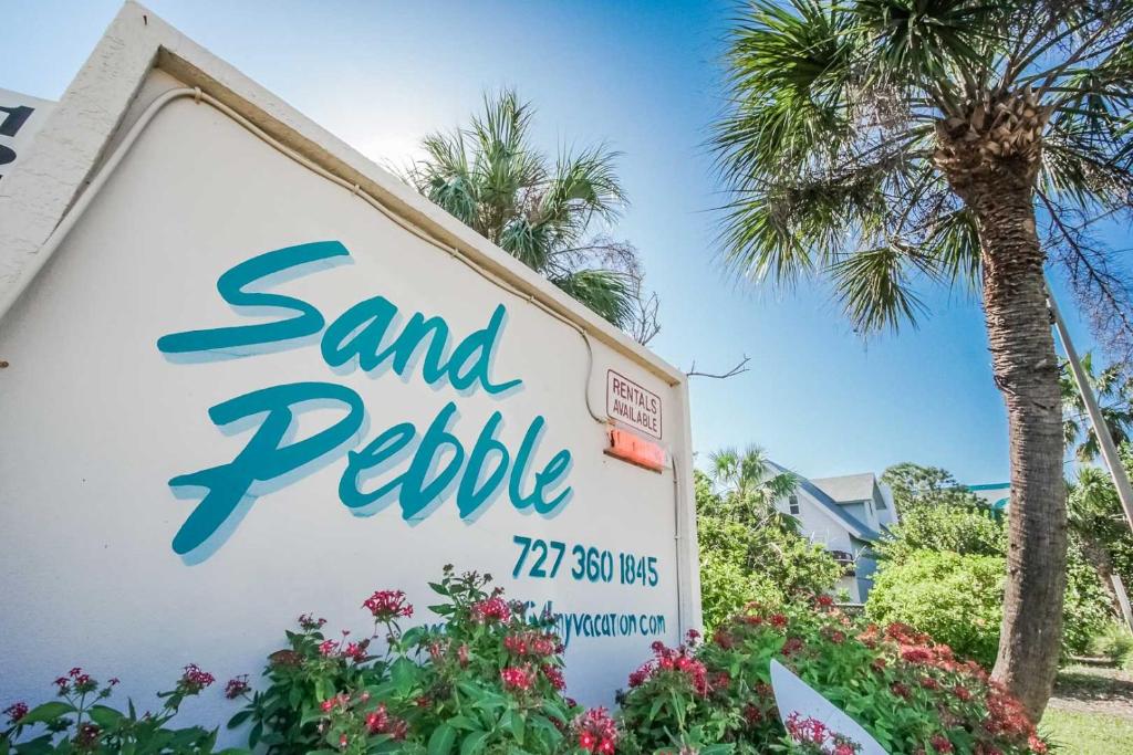 a sign for a sand pebble hotel with palm trees at Sand Pebble Resort in St Pete Beach