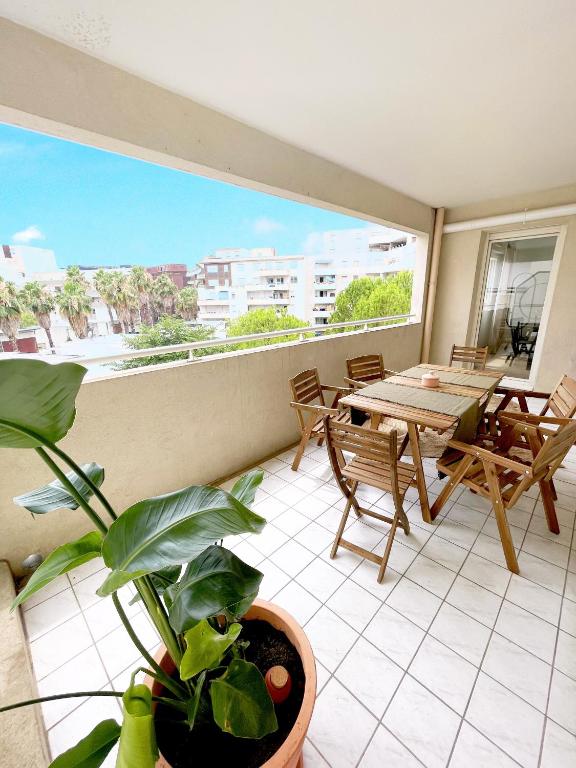 un balcon avec une table et des chaises et une grande fenêtre dans l'établissement T3 Bohème au cœur de Port Marianne, à Montpellier