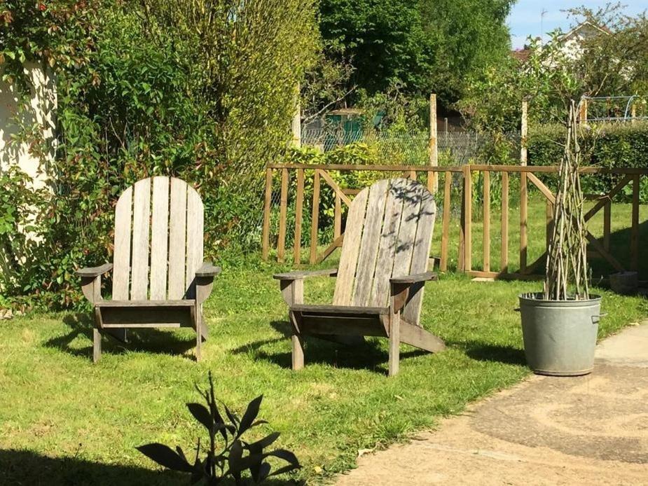 two wooden chairs sitting in the grass next to a fence at Gite 65 in Chartres