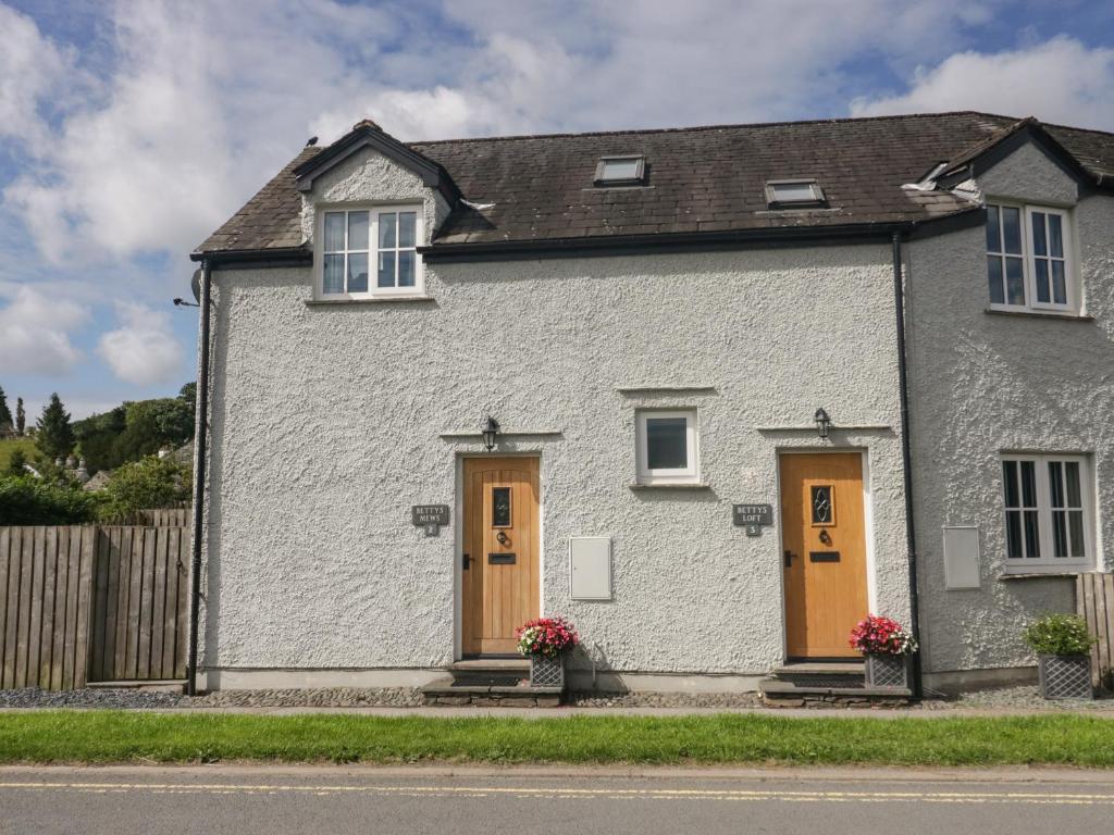 a white house with orange doors and a fence at Betty's Mews in Ambleside