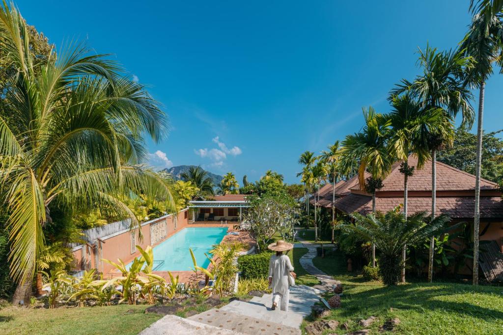 eine Villa mit einem Pool und einer Person im Hof in der Unterkunft Baan Taranya Koh Yao Yai - SHA Extra Plus in Ko Yao Yai