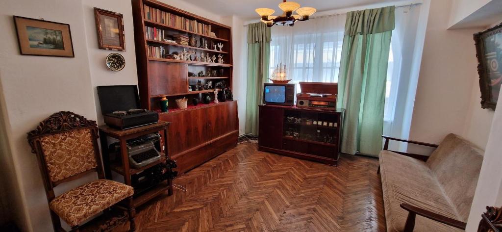 ein Wohnzimmer mit einem Sofa, einem TV und einem Bücherregal in der Unterkunft Domum - The Comunist Apartment in Bukarest