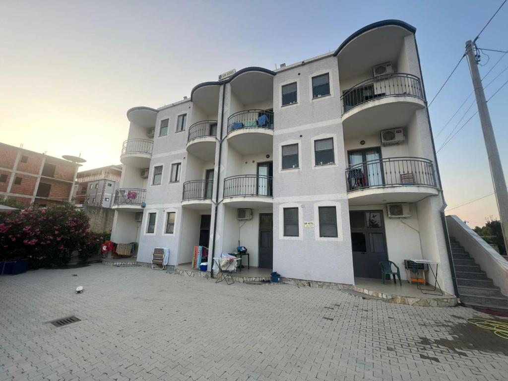 een groot wit gebouw met balkons in een straat bij Sar Hotel, Velipojë in Velipojë