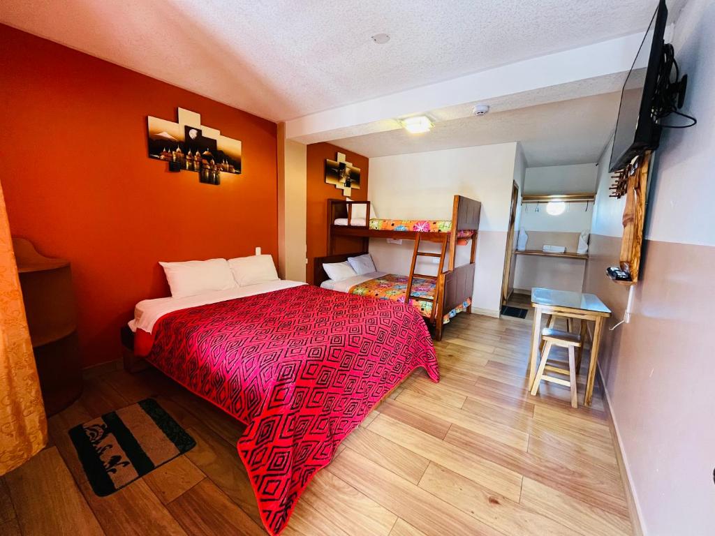 a bedroom with a red bed and a small table at Hostal Alpachaca - New Quito Airport in Tababela