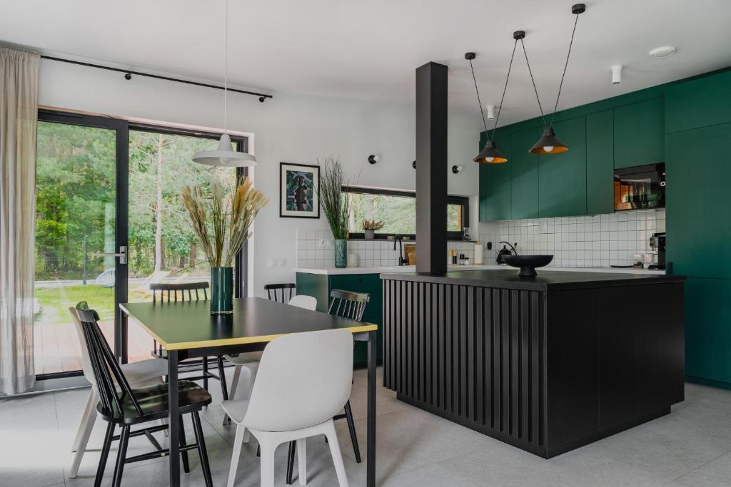 a kitchen with green cabinets and a table and chairs at Domek z basenem nad Bugiem in Błonie