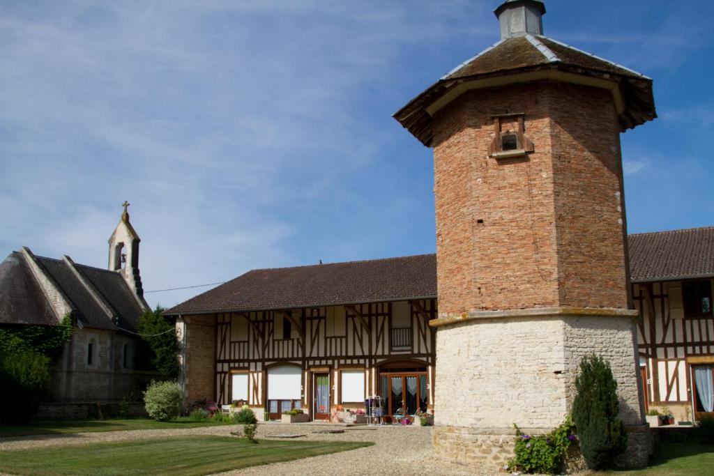 Stary budynek z ceglaną wieżą przed nim w obiekcie Gîtes du Château de Crespy 