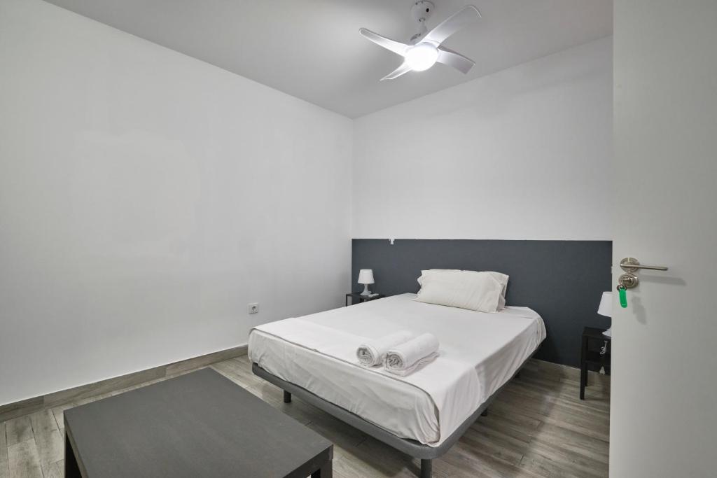 1 dormitorio con cama blanca y ventilador de techo en Núñez de Arce habitaciones, en Madrid