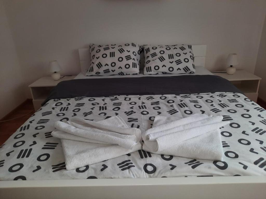 Bett mit schwarzweißer Bettwäsche und Kissen in der Unterkunft Apartman Petković in Višegrad
