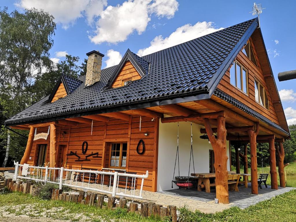 a log cabin with a black roof at Dom Na Korzeniu 