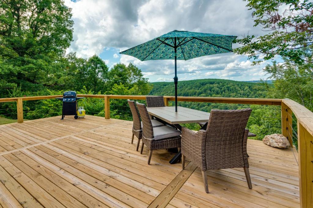 una terraza de madera con mesa, sillas y sombrilla en Searcy Vacation Rental with Deck and Water Views!, en Searcy