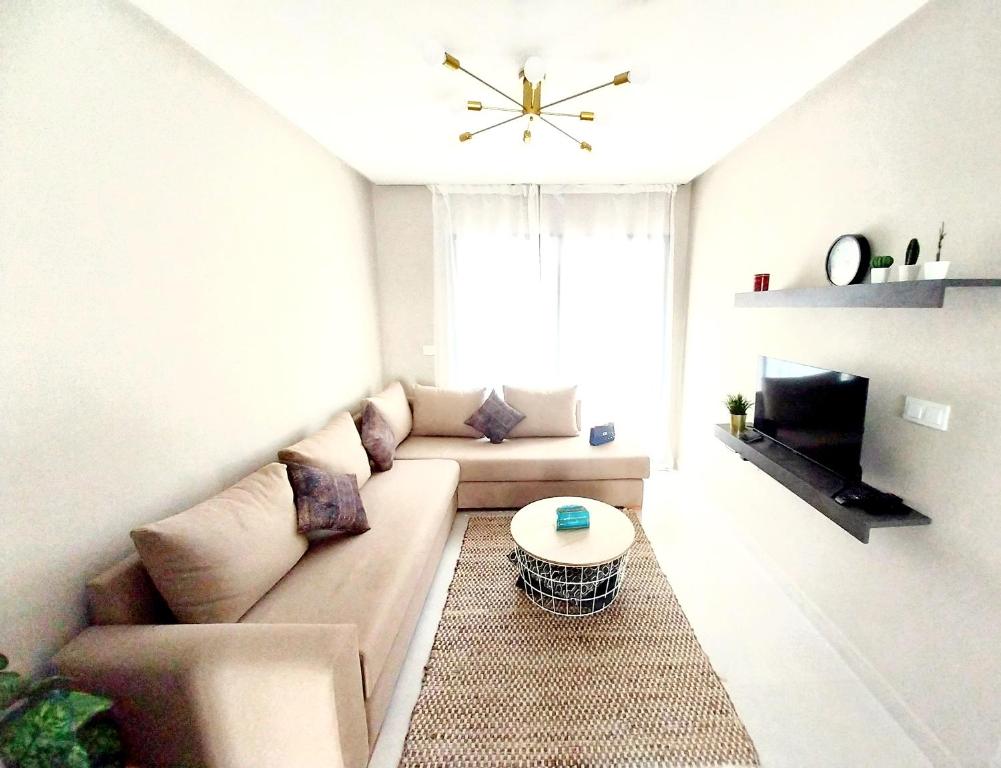 ein Wohnzimmer mit einem Sofa und einem TV in der Unterkunft Cosy appartement proche de l'aéroport mohamed 5 in Deroua