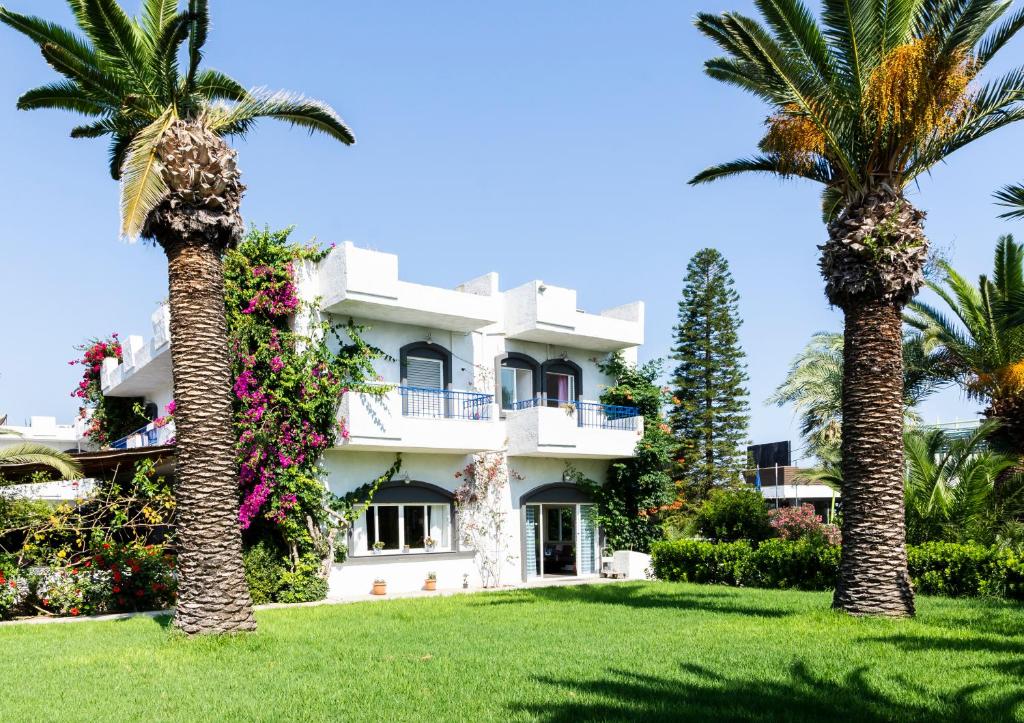 a building with palm trees in front of it at Gorgona Hotel in Amoudara Herakliou