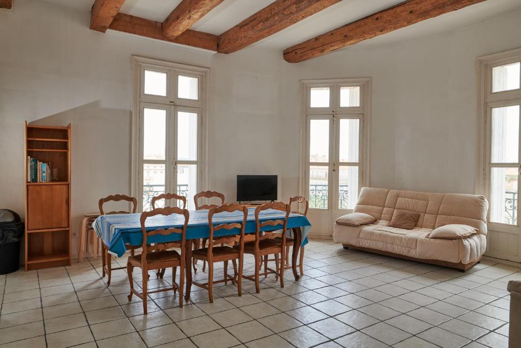 un salon avec une table, des chaises et un canapé dans l'établissement Grand Appartement Au Coeur de Sète, à Sète