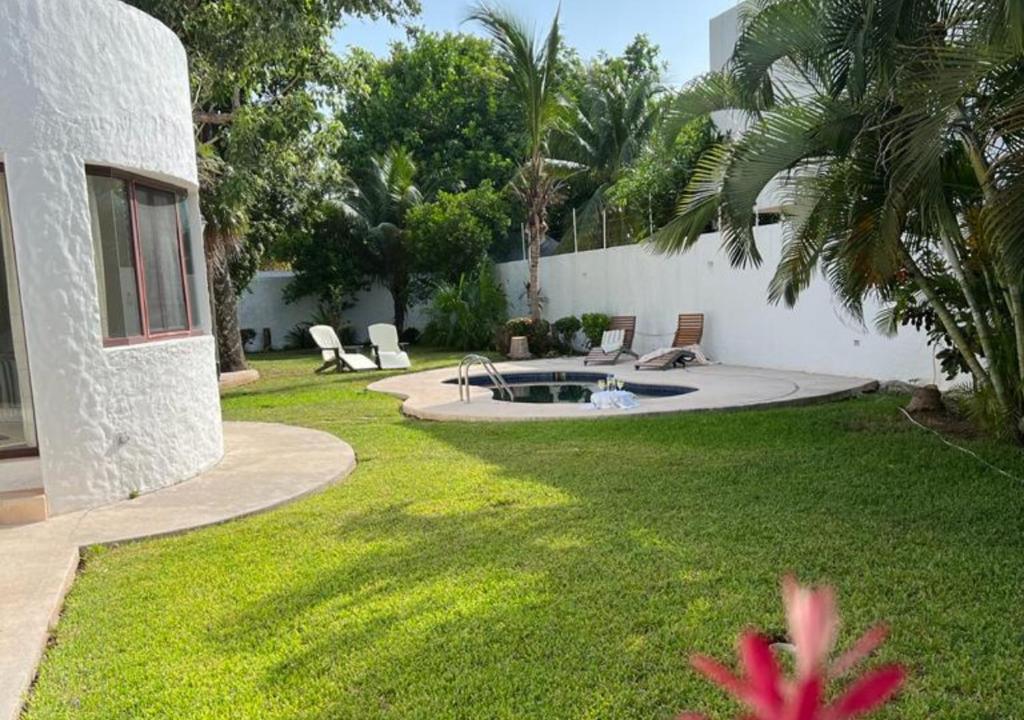un patio con una piscina con sillas y una casa en Casa Iola, en Cancún