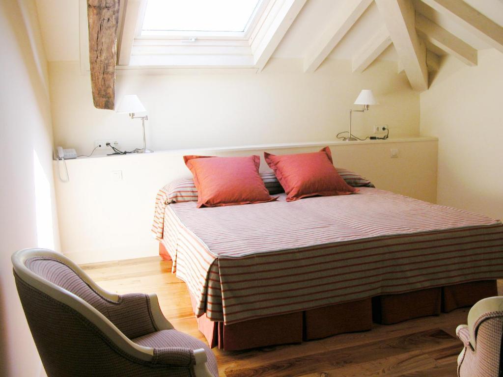 1 dormitorio con 1 cama con almohadas rojas y 2 sillas en Posada Villa Esperanza, en Liérganes