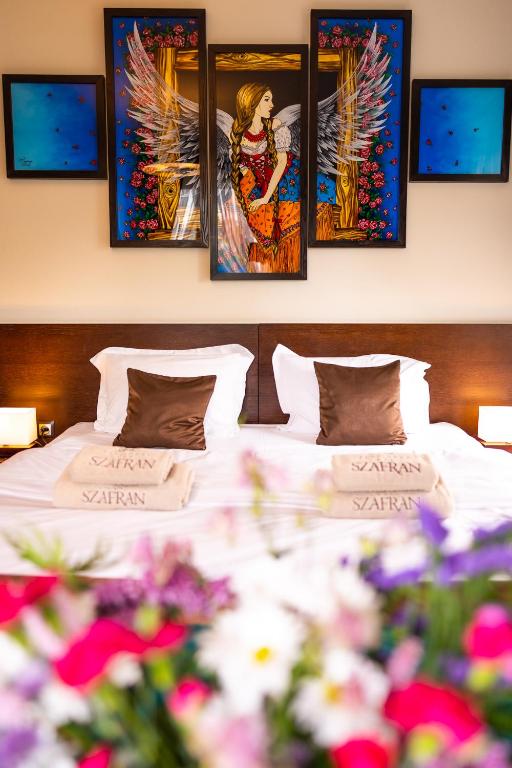 a bedroom with a bed with four paintings on the wall at Willa Szafran in Dzianisz