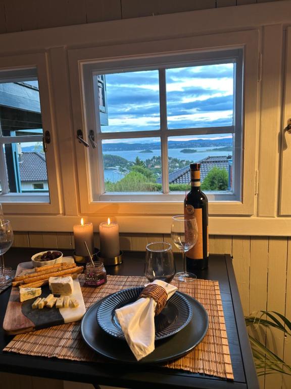 The View Guesthouse at Ekeberg -10 min by tram to Oslo S في أوسلو: طاولة مع زجاجة من النبيذ وصحن من الجبن