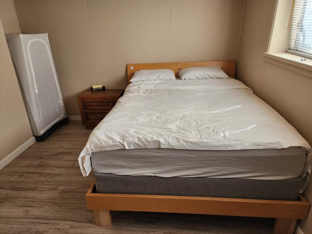 a bedroom with a large bed with a wooden headboard at Economical Homestay in Burnaby