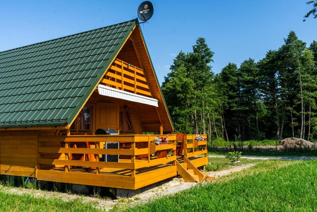 a large wooden cabin with a green roof at Nad Strumykiem in Sasino