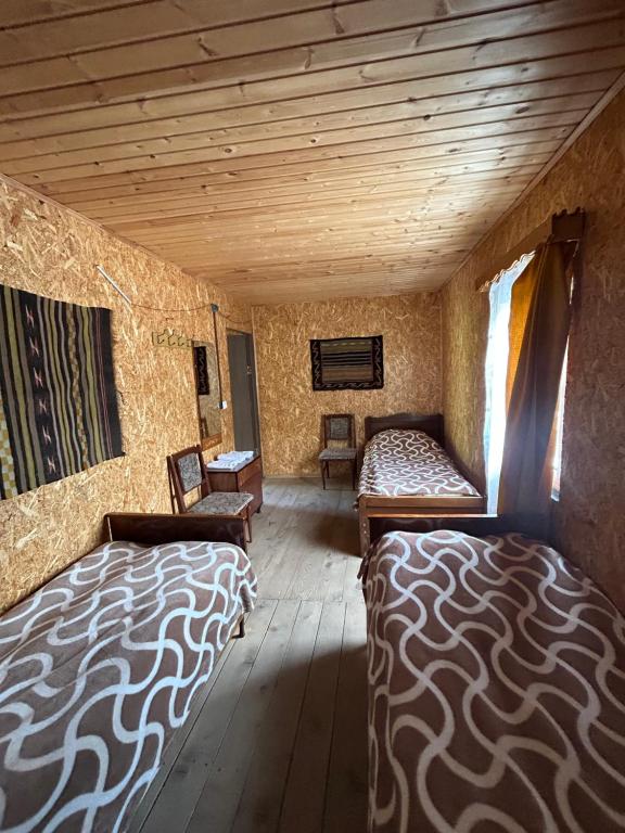 Camera con 2 letti e soffitto in legno. di Shio's Stonehouse in Tusheti a Tusheti