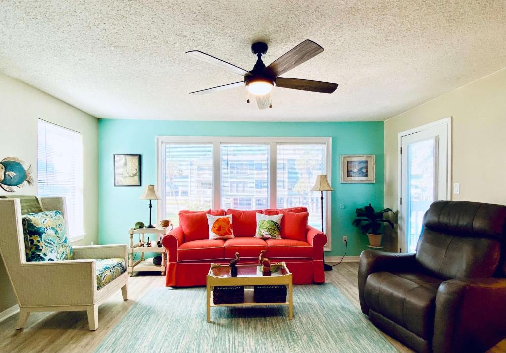 - un salon avec un canapé rouge et un ventilateur de plafond dans l'établissement Sea Oats B106 by ALBVR - Great renovation and tons of space in this 2BR 2BA condo - Outdoor Pools, Pier, and Dedicated Beach Access, à Gulf Shores