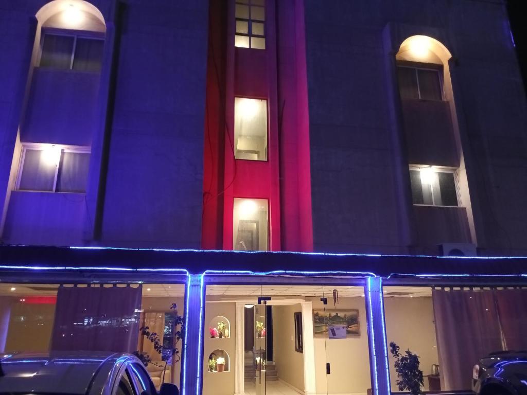 阿可賀巴的住宿－ورده，享有大楼的夜间景色,设有红色的门
