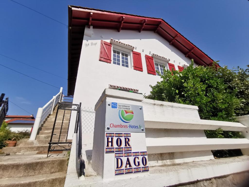 Uma casa branca com um cartaz à frente. em Chambres d'hôtes "HOR DAGO" près de la gare d'Hendaye avec le petit-déjeuner em Hendaye