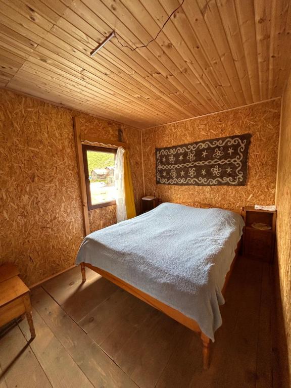 Bett in einem Zimmer mit Holzdecke in der Unterkunft Shio's Stonehouse in Tusheti in Tusheti