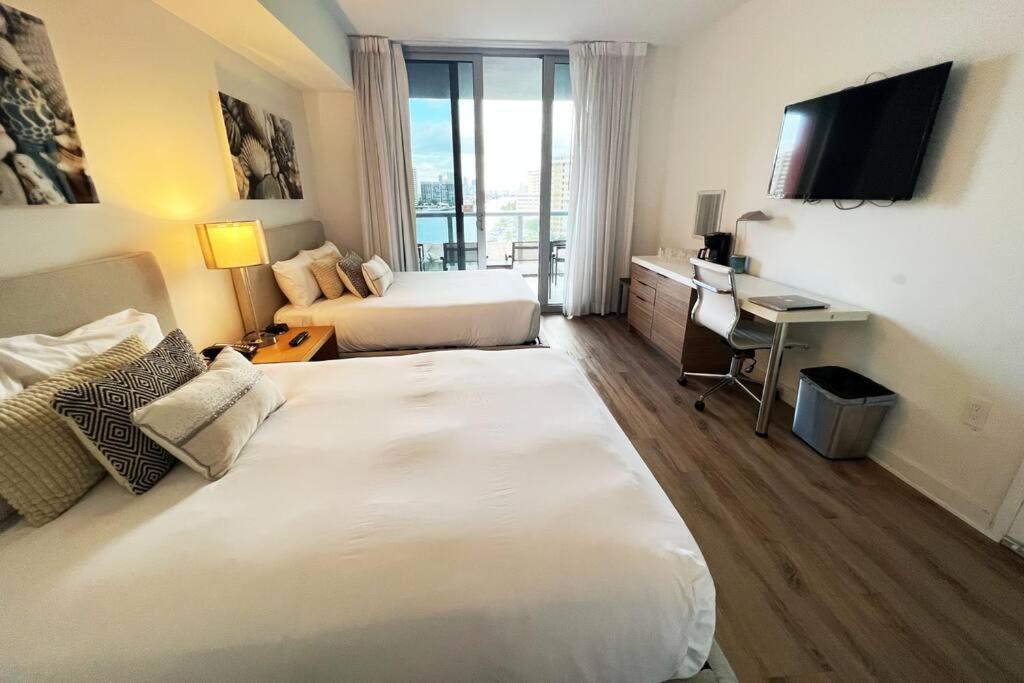 um quarto de hotel com duas camas e uma secretária em Beautiful studio in Hallandale Beach em Hallandale Beach