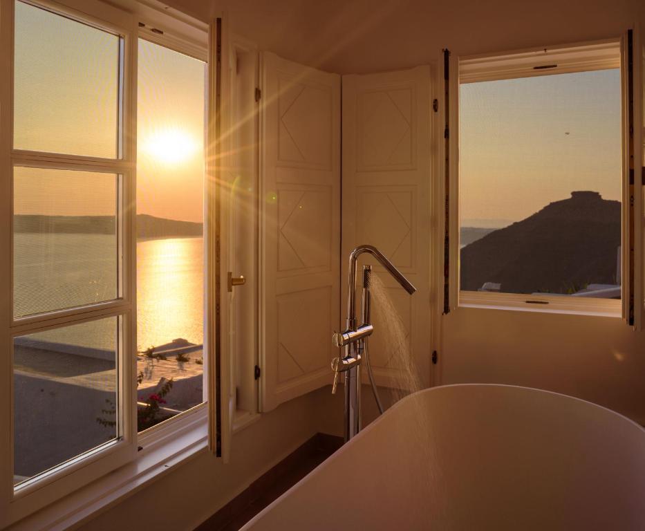 a bath tub in a bathroom with a window at Elia Family Suites in Fira