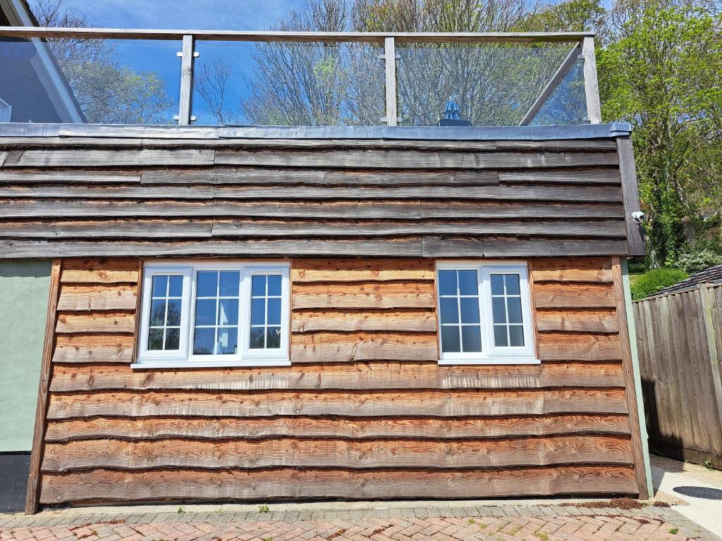 a log cabin with two windows and a fence at Sylvan Seas in Whitwell