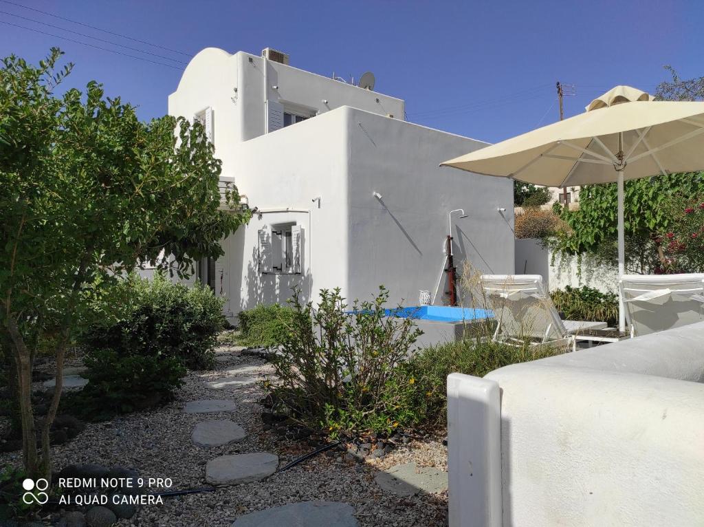 a white house with an umbrella and a pool at JB Villa in Mesaria