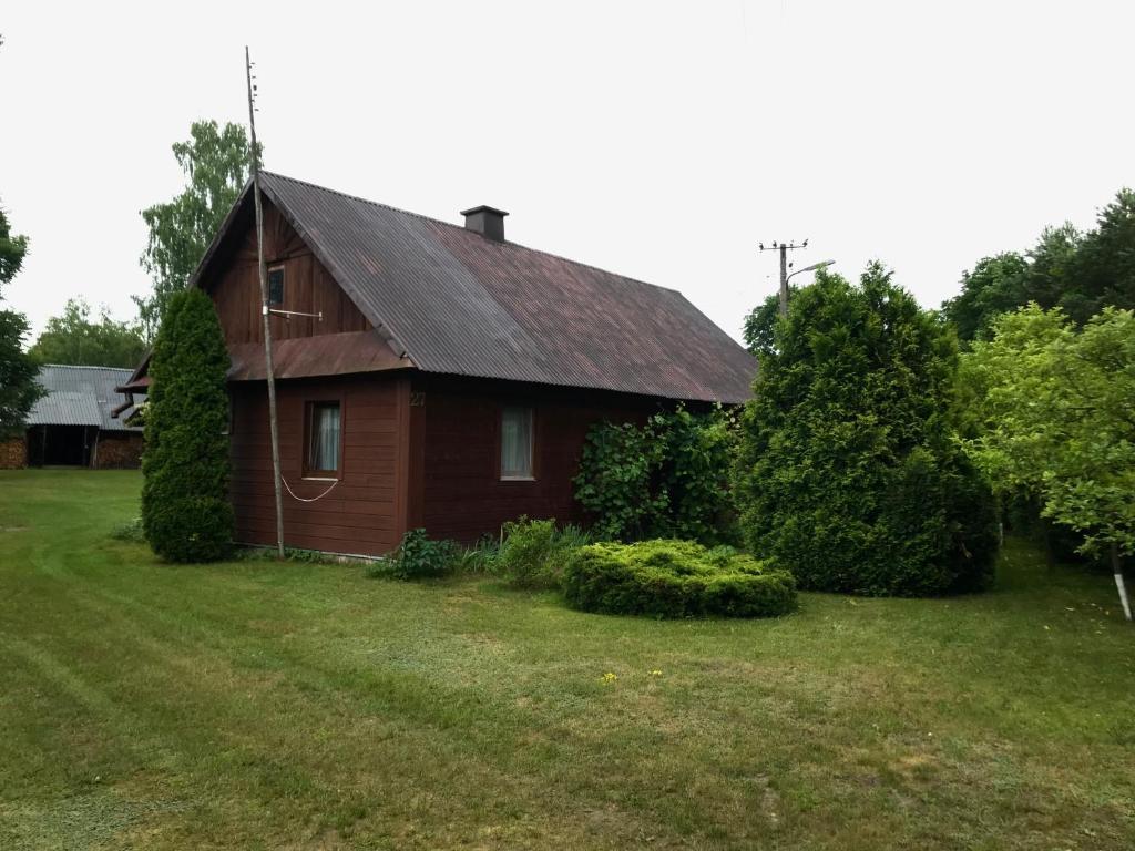 a small red house in a grassy yard at Wiejski Domek na Roztoczu 