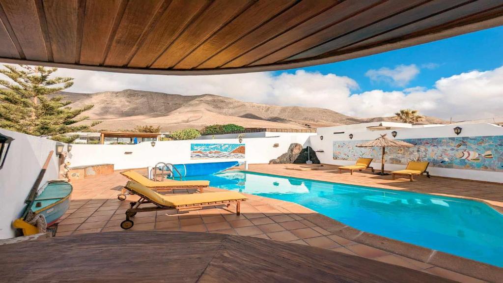 a swimming pool with a view of the mountains at Bungalow Allende Famara con piscina privada y AC in Famara