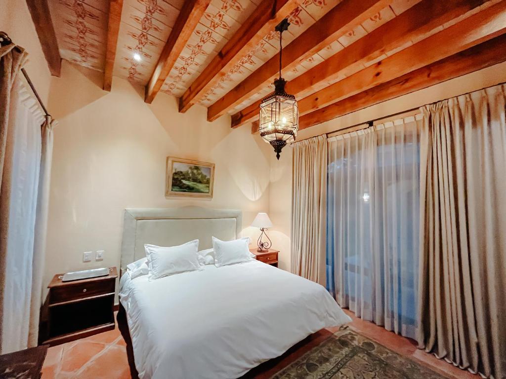 a bedroom with a white bed and a large window at Hacienda Los Arcangeles in San Miguel de Allende
